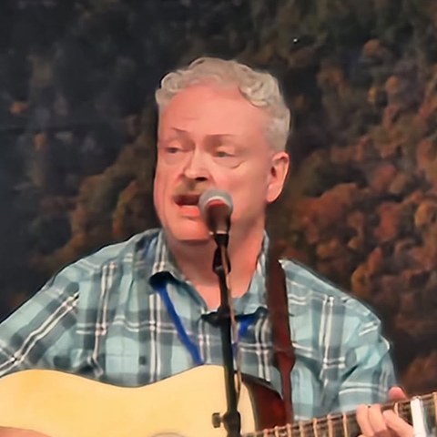 Tim Stafford singing and playing guitar on stage